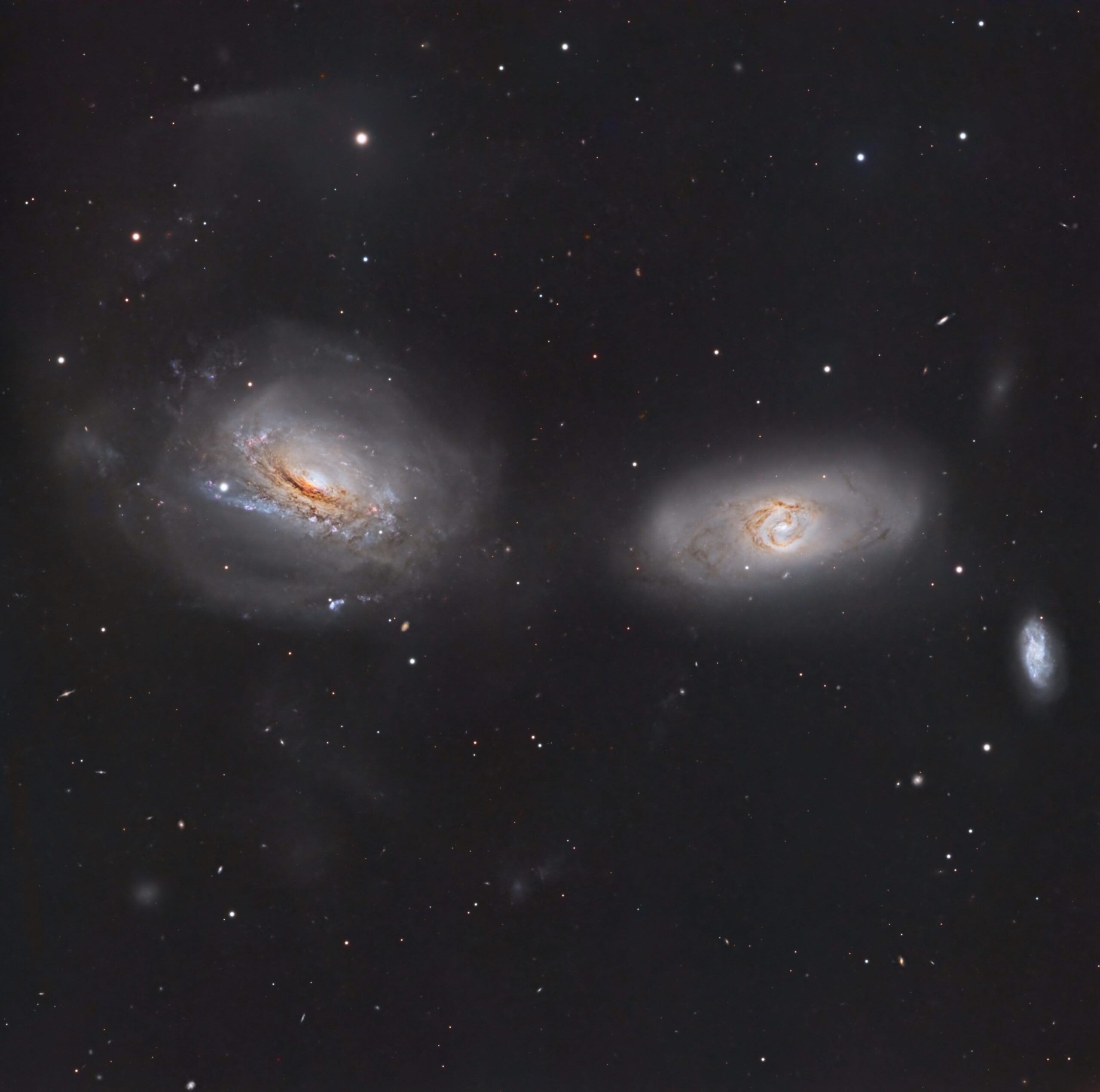Two spiral galaxies in a star-filled sky, with dusty, winding arms toward the bottom edge of the image.